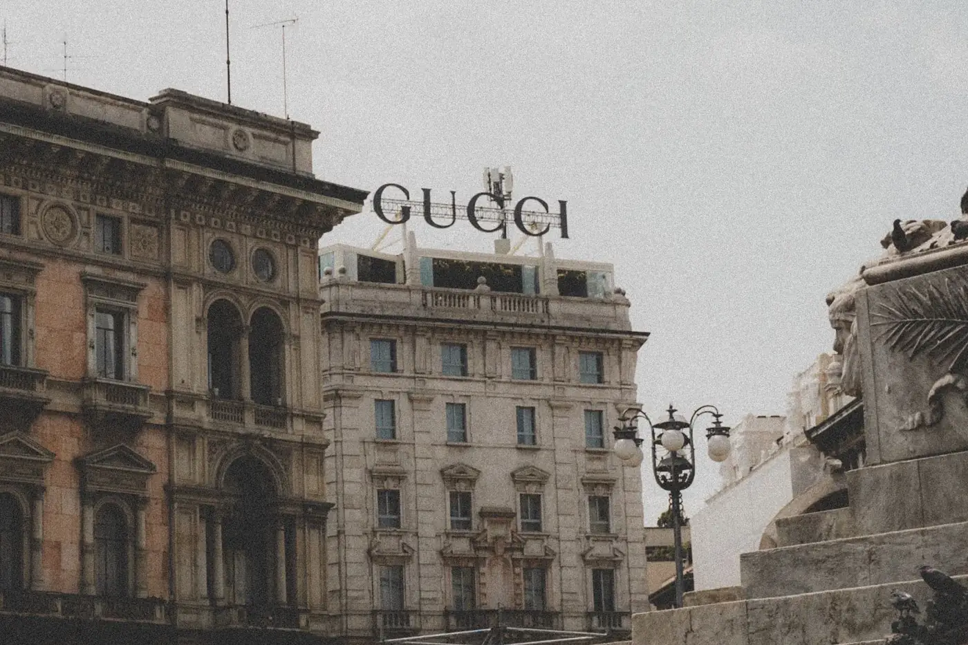Urban scene featuring historic architecture and Gucci signage under a cloudy sky.