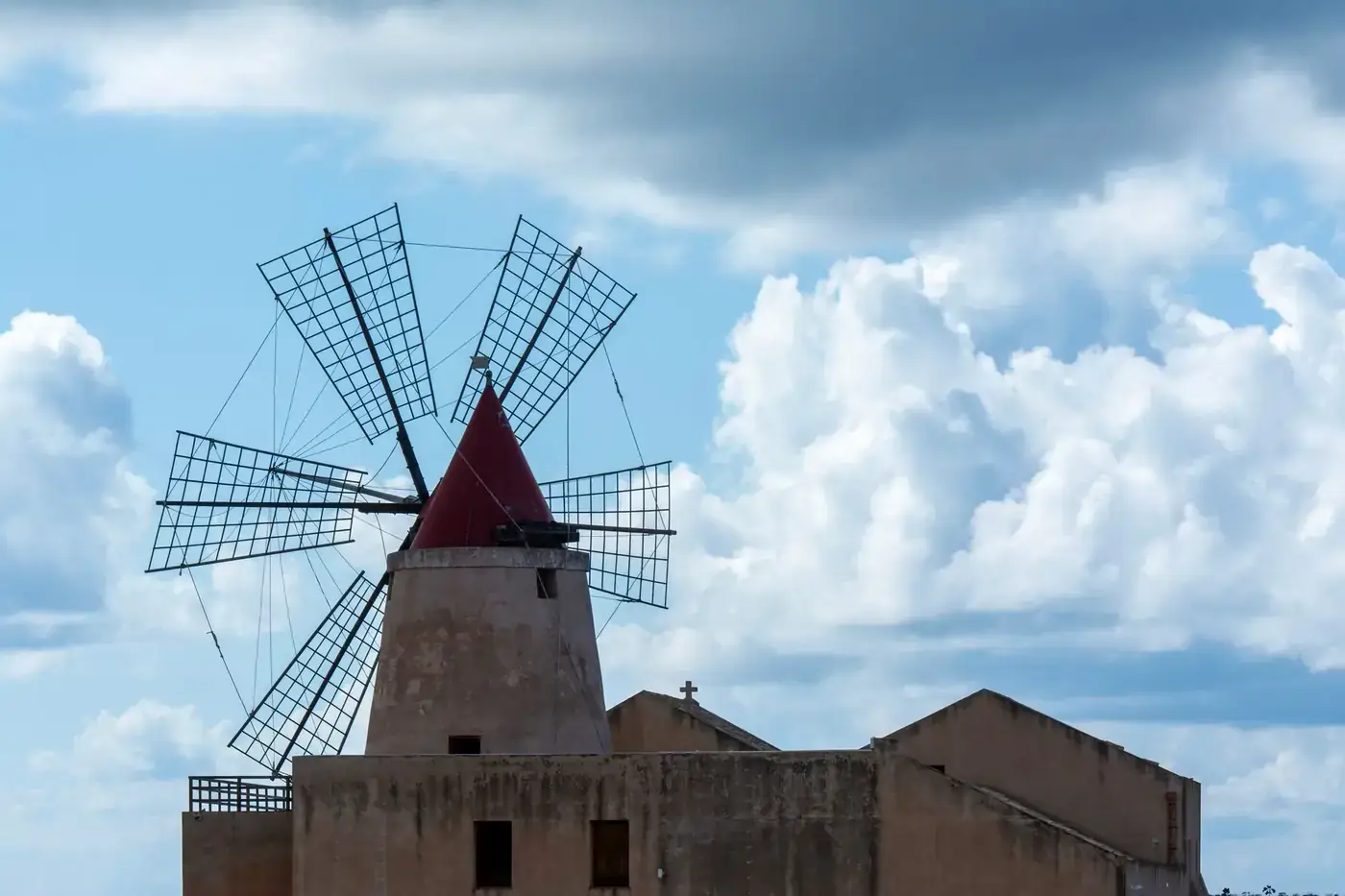 Iconic windmill in Nubia, Sicily against a vibrant cloudy sky, showcasing Italian historical architecture.