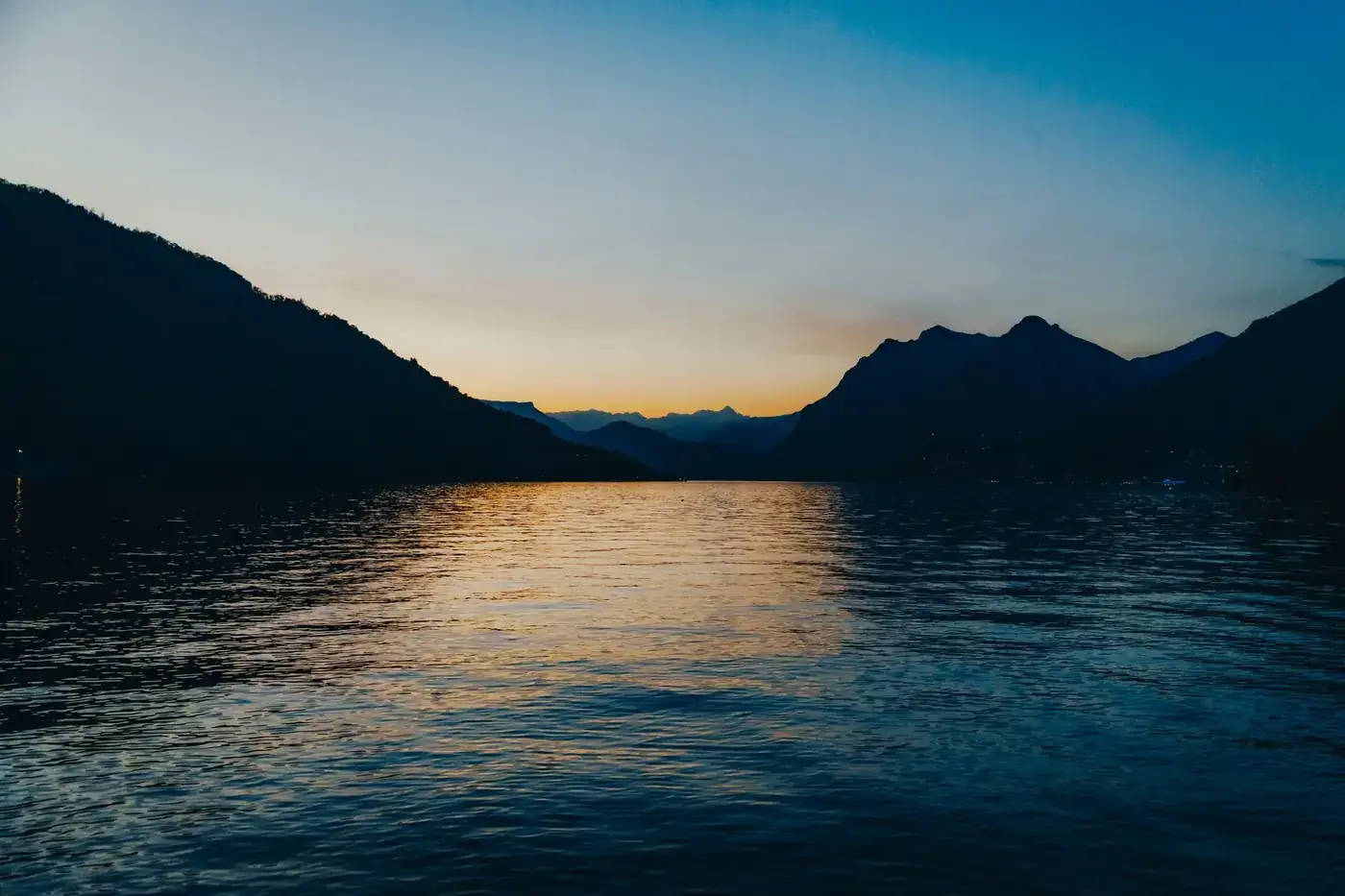 Tranquil sunset view over Lake Iseo in Lombardy, Italy, showcasing vibrant colors and peaceful waters.