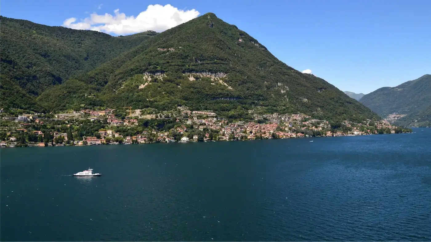 A beautiful panoramic view of Lake Como with surrounding hills and a boat on the water.