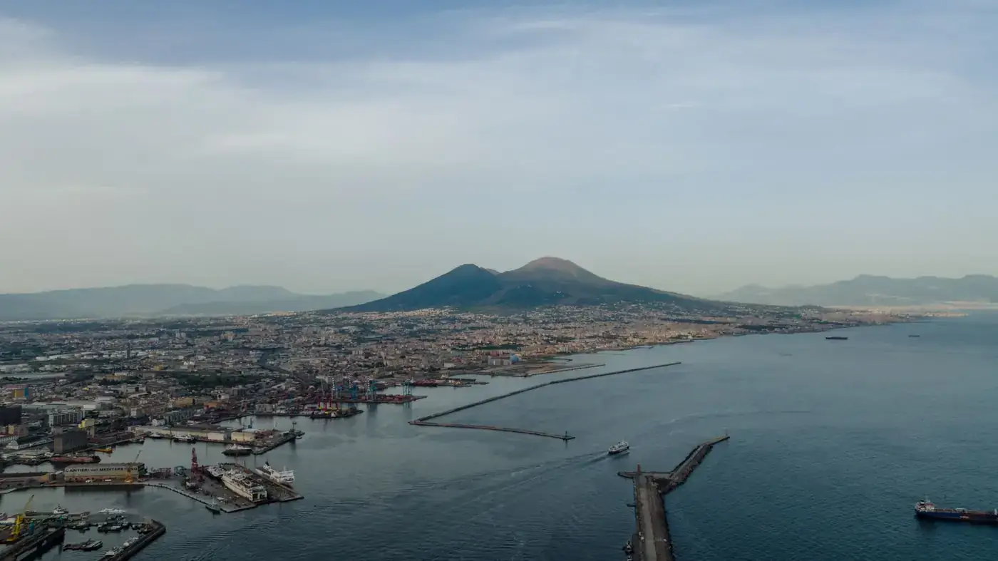 Stunning aerial shot of Mount Vesuvius with Naples cityscape and bay, capturing serene seascape and iconic volcano.