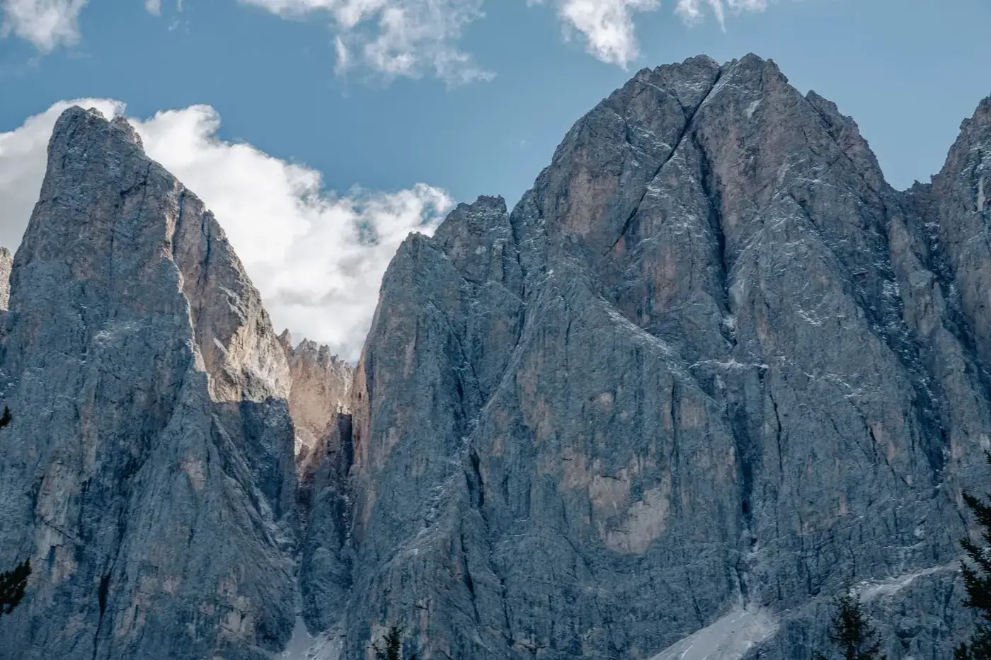 Stunning view of rocky Dolomites peaks against a blue sky with clouds, ideal for nature photography enthusiasts.