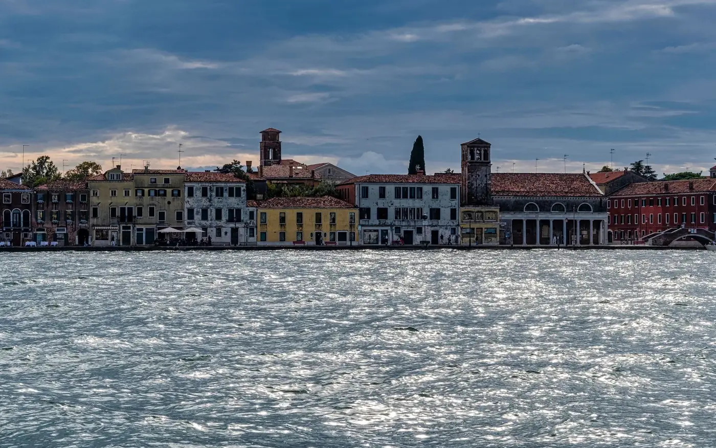 Charming Venetian waterfront with historic buildings under a soft, cloudy sky.