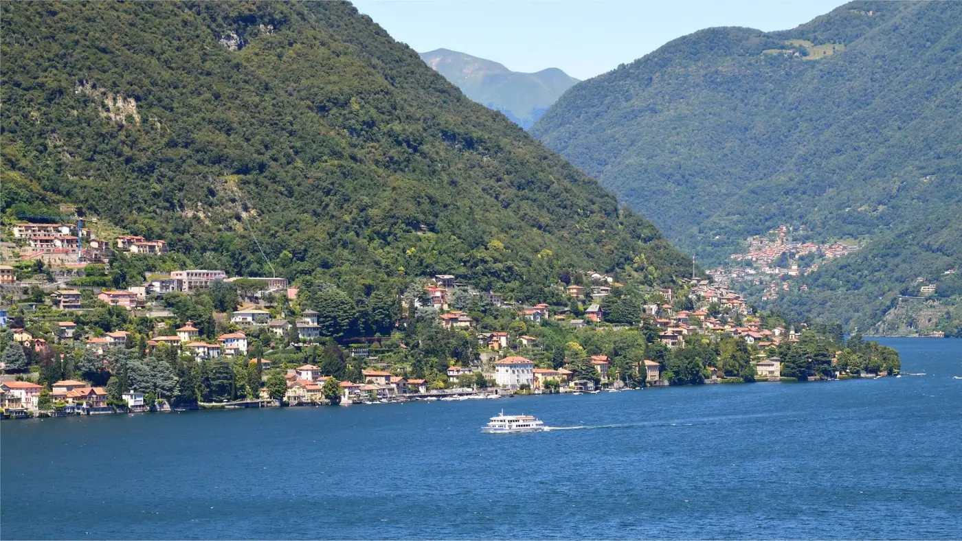 Panoramic view of Lake Como with towns nestled amidst lush hills and a serene blue lake.