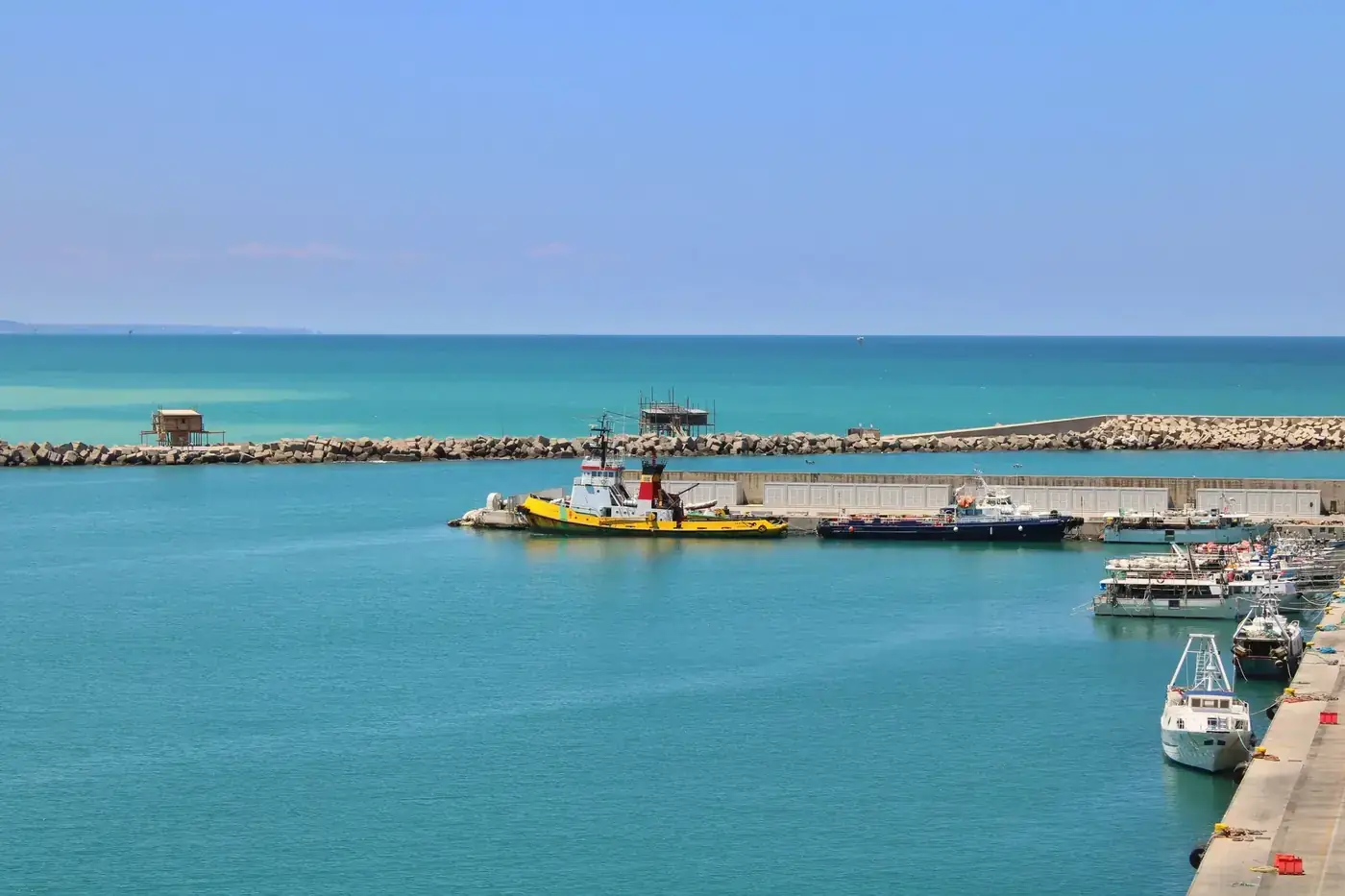 A vibrant seaside view of Vasto Marina harbor with boats moored under a clear blue sky.