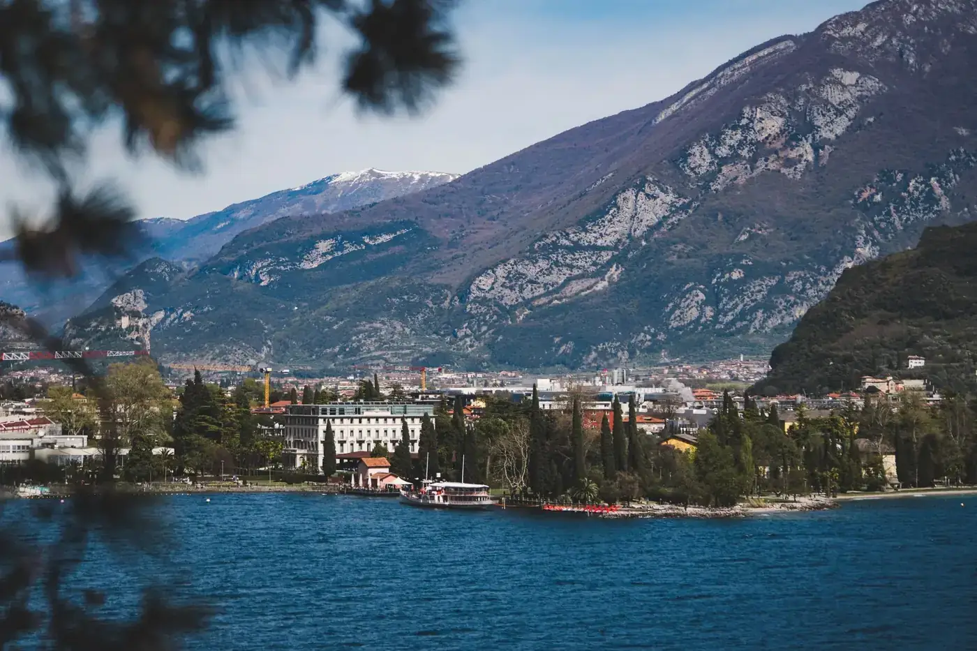 A serene view of Lake Garda surrounded by mountains and lush greenery in northern Italy.