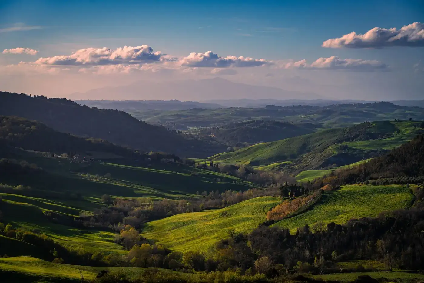 Panoramic view of rolling hills in Volterra, Tuscany under a blue sky.