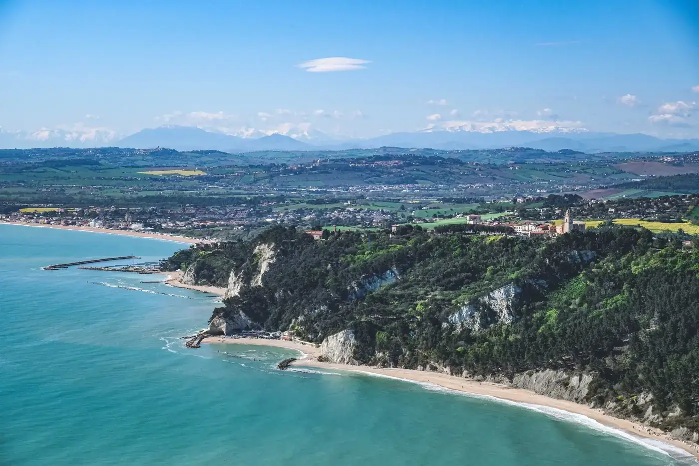 Stunning aerial shot of a coastline with lush greenery and a vibrant blue sea.