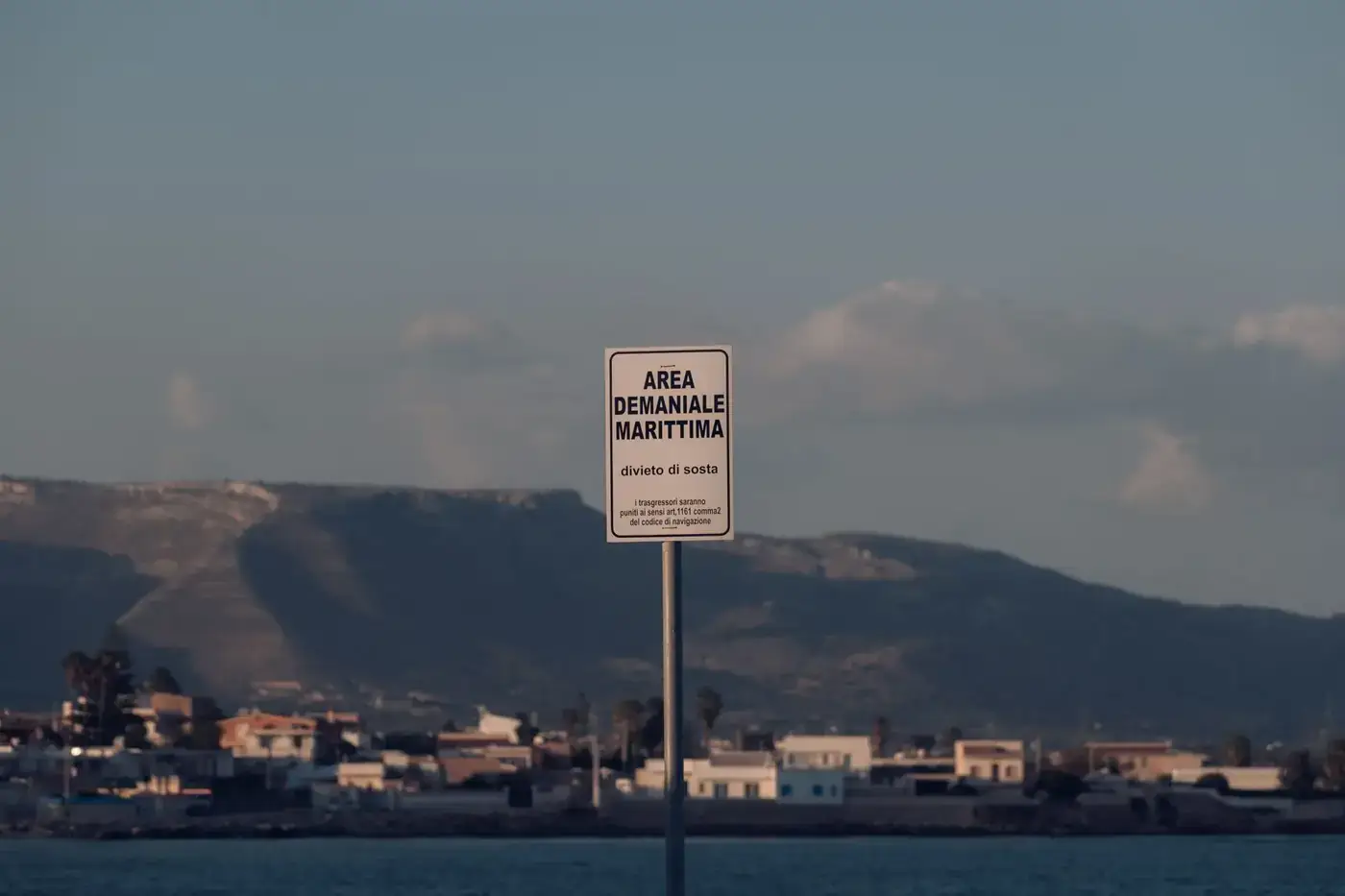 Maritime area sign at Calabernardo's coastline, framed by Sicilian hills and seascape.