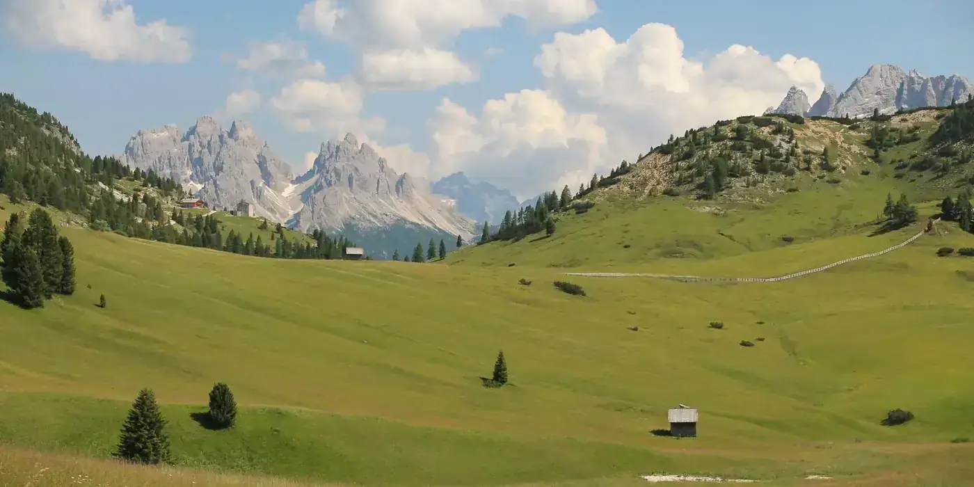 Captivating landscape of the Dolomites with lush meadows and rustic huts in San Candido, Italy.