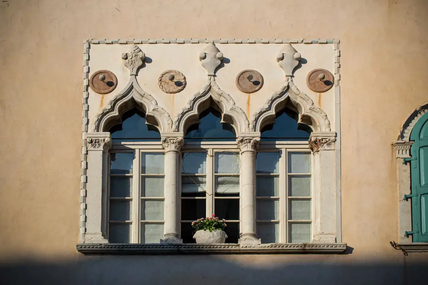 Elegant Gothic-style window facade in Venzone, Friuli-Venezia Giulia, Italy, showcasing historic architecture.