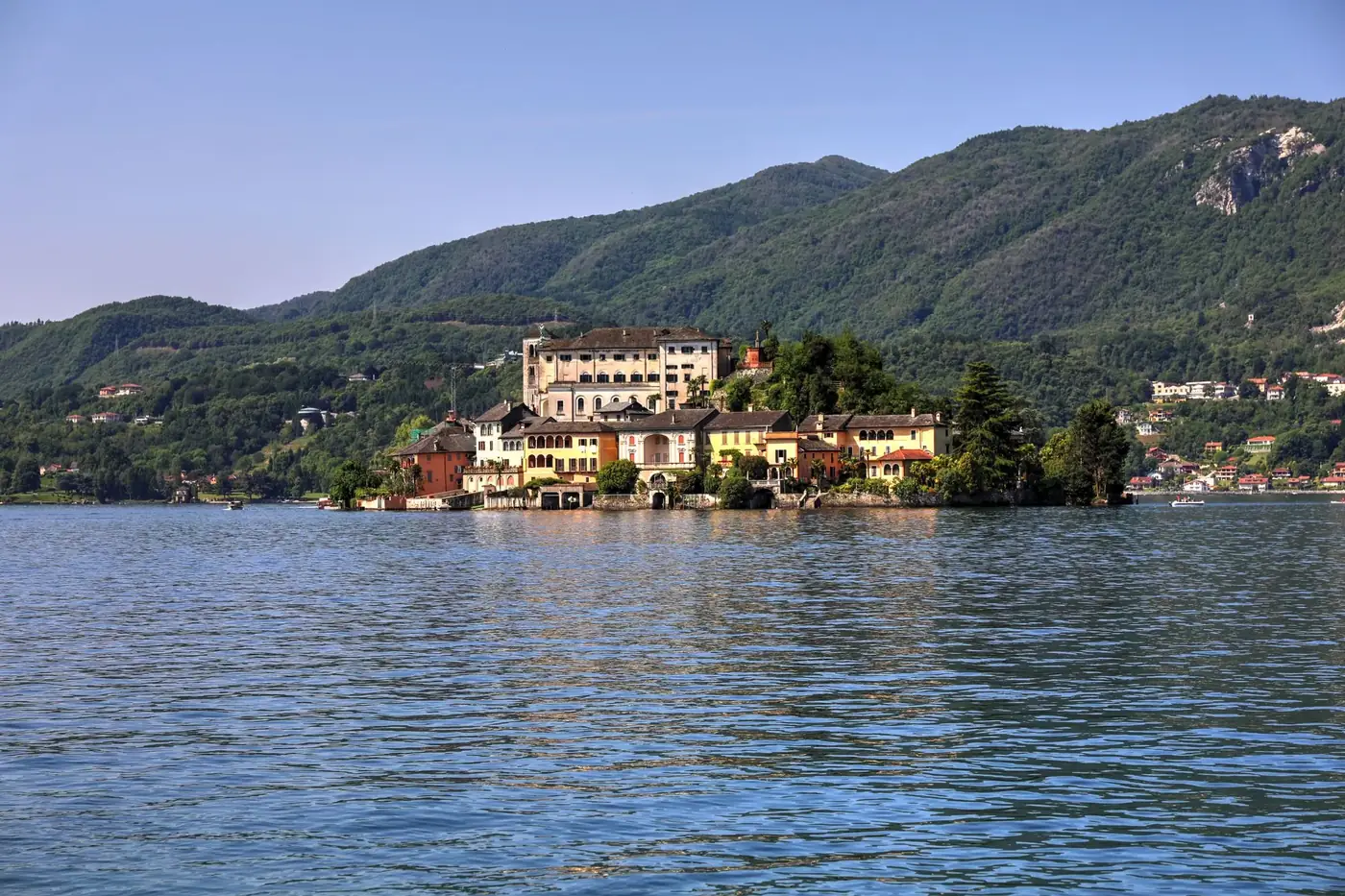 A picturesque island set against a backdrop of mountains and calm lake waters.