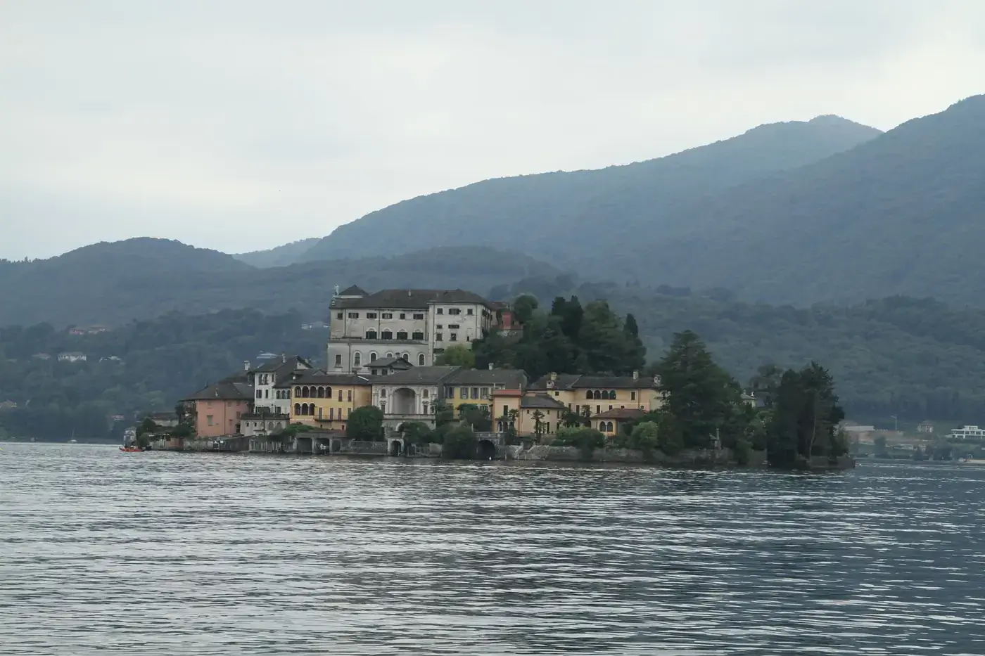 Serene view of an island with historical architecture on a tranquil lake surrounded by mountains.