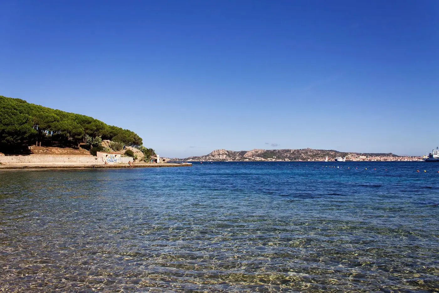 Breathtaking coastal scene in Sardinia, Italy with clear blue waters and lush greenery.