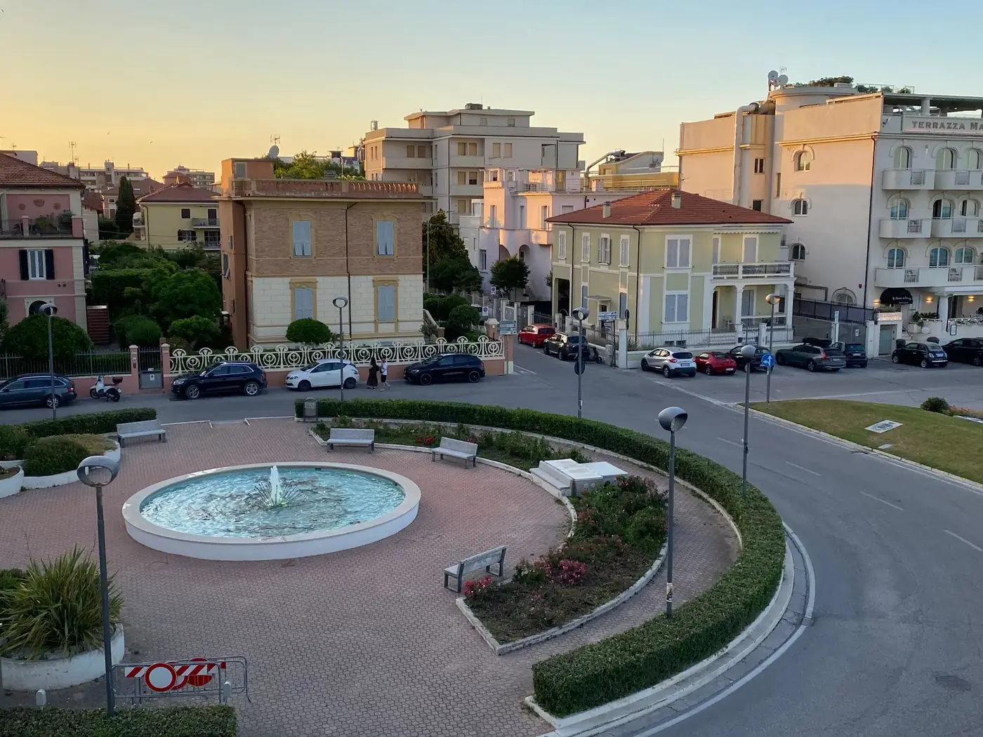 A beautiful sunset view of an Italian piazza with a fountain and classic architecture, offering a serene cityscape.