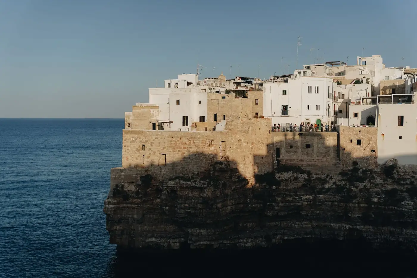 Explore the beauty of a traditional cliffside town overlooking the sea, bathed in warm sunset light.