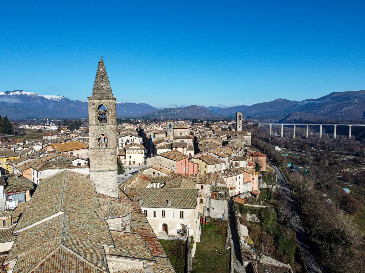 Scenery of old stone castle with spire surrounded by small cottages of Rovereto town surrounded by rough hills under blu