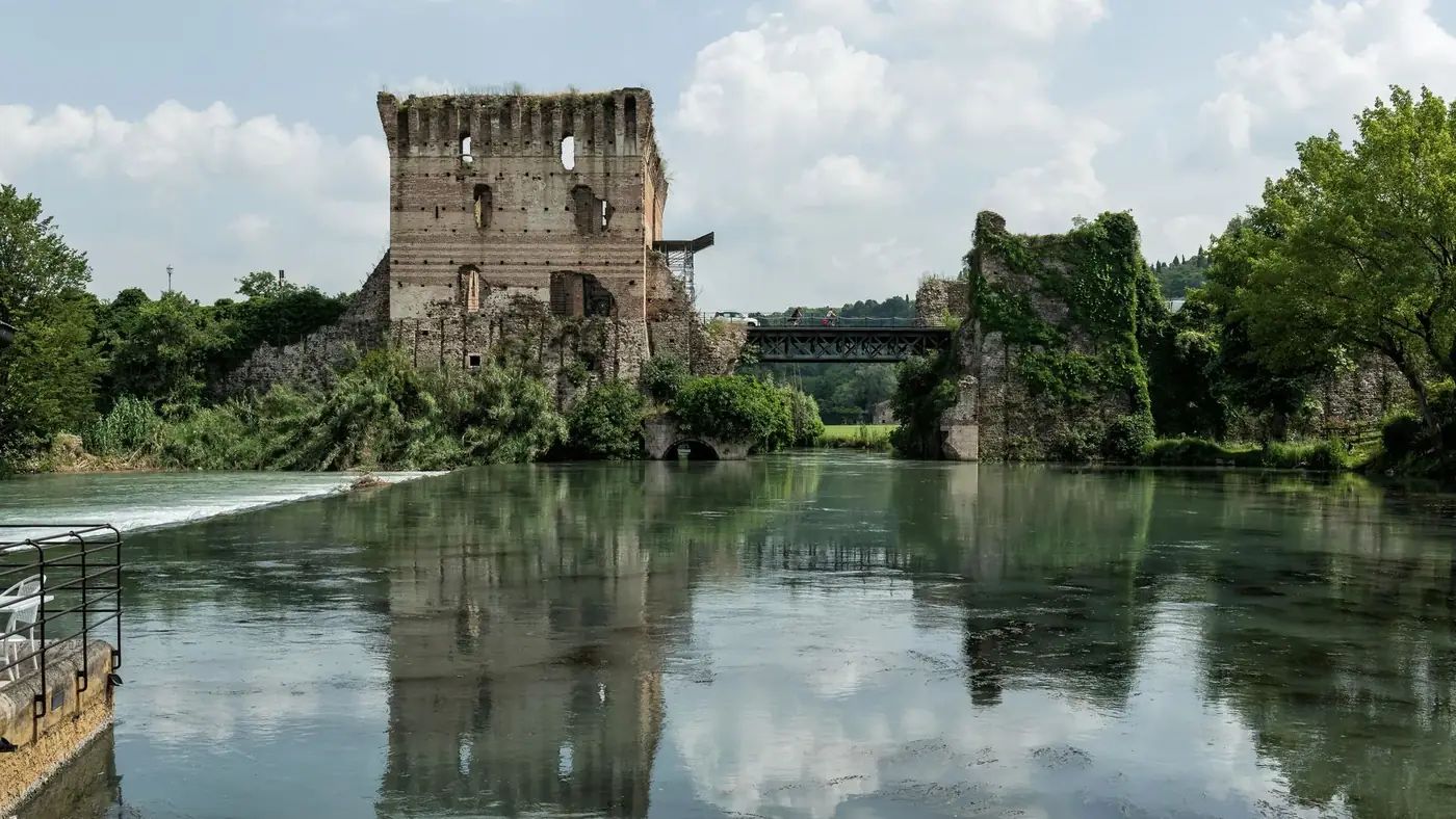 Discover the serene beauty of ancient ruins by the river in Valeggio sul Mincio, Italy.