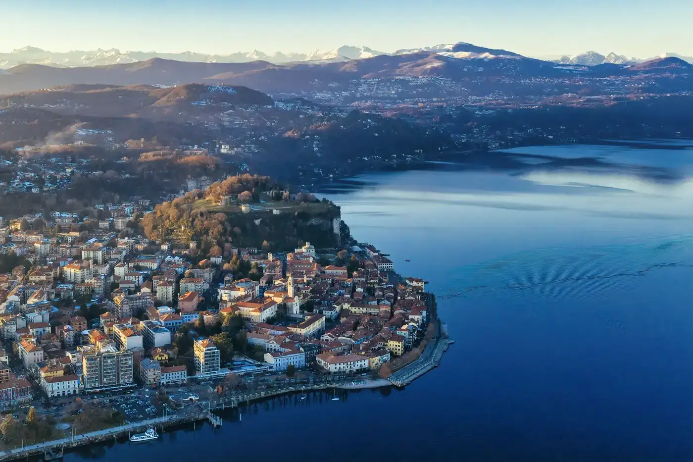Aerial view of Arona by Lake Maggiore with mountains in the background.