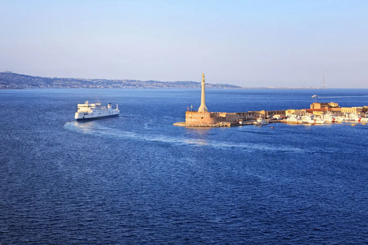 Stunning aerial view of Messina Harbor featuring a cruise ship near a historic monument.