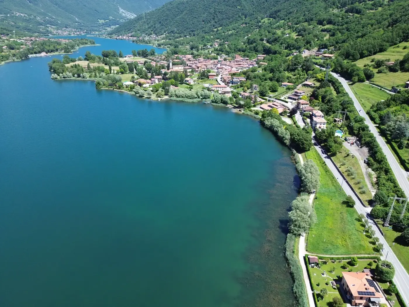 Stunning aerial view of Monasterolo del Castello, Italy, showcasing lush greenery and the pristine lake.