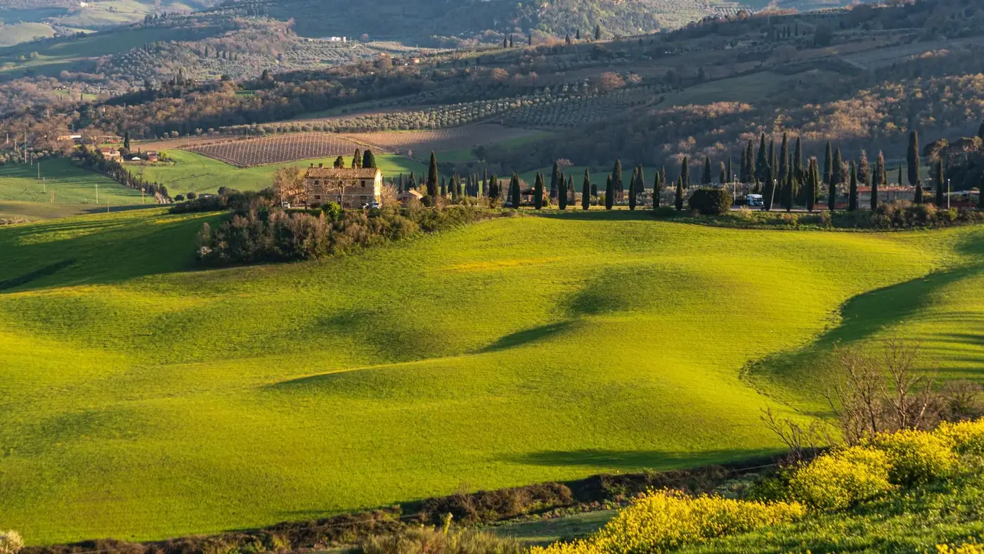 Capture the serene landscape of Tuscany's rolling hills in spring, featuring lush greenery.