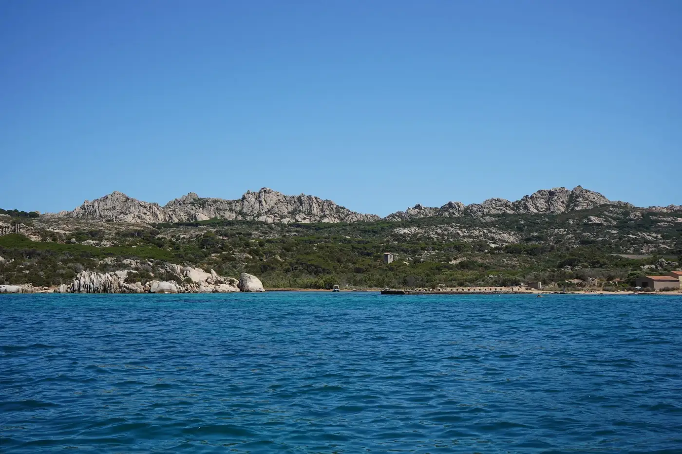 Explore the stunning, rocky coastline of Sardinia, Italy, with clear blue waters and mountainous terrain.