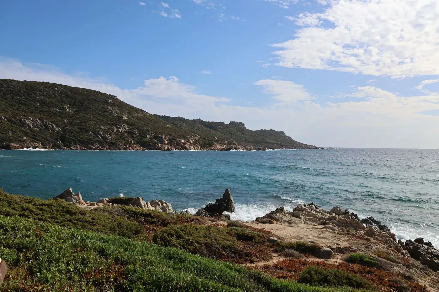 Scenic coastline with rugged rocks and turquoise sea under a bright blue sky.