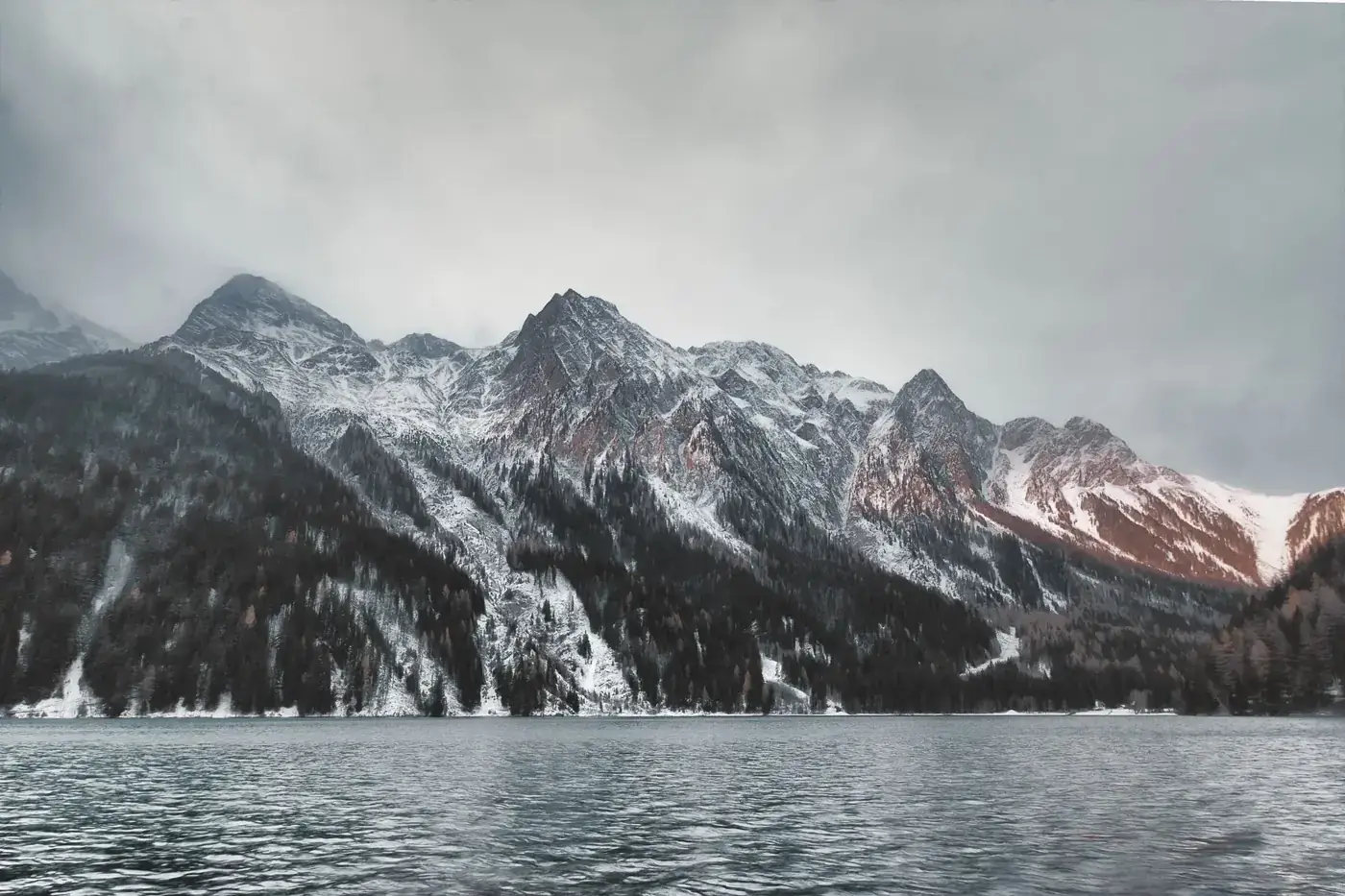 Capture of snow-covered peaks and serene lake in Trentino-Alto Adige, Italy, during winter.