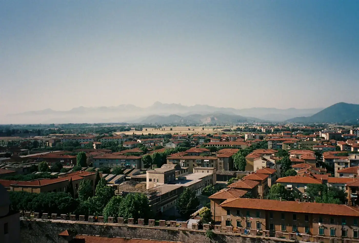 Scenic aerial view of Pisa, Italy with lush Tuscan countryside and rolling hills in the background.