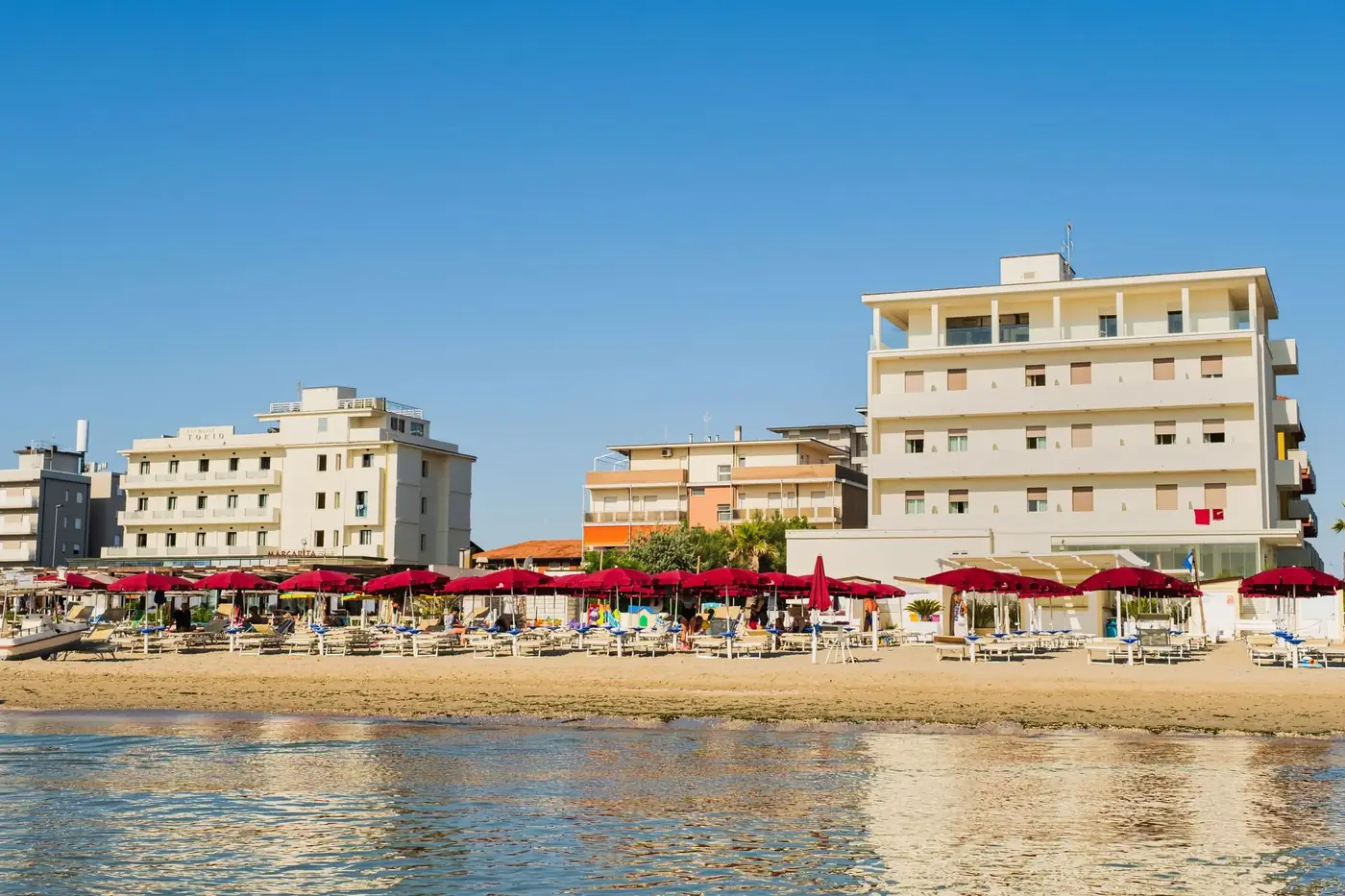 Stunning Lido di Savio beachfront view with hotels and umbrellas under a clear summer sky.