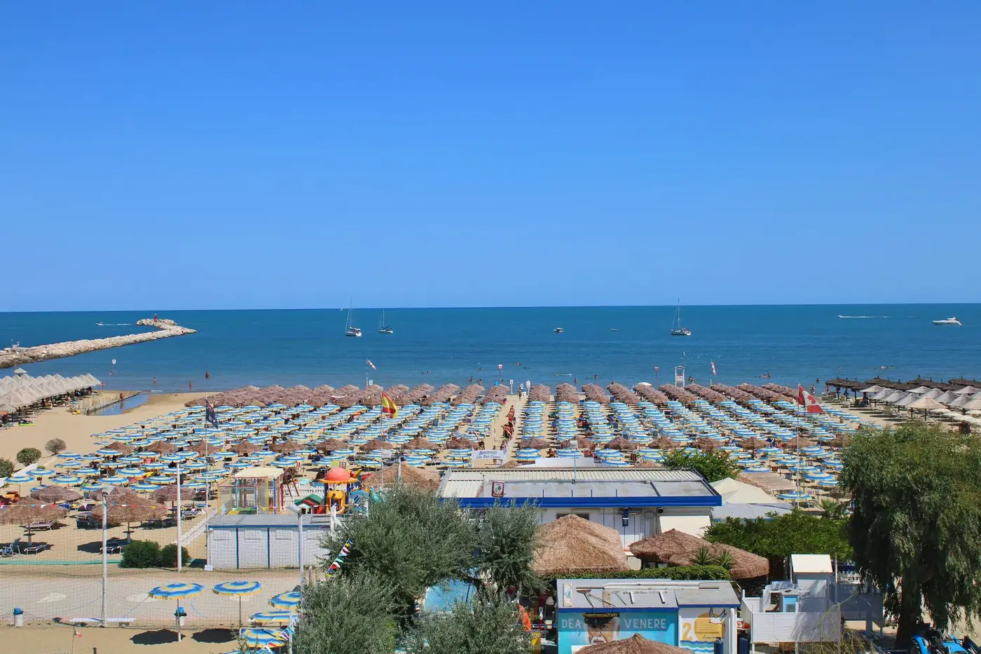 Aerial view of crowded Ortona beach with umbrellas and boats on a sunny summer day.