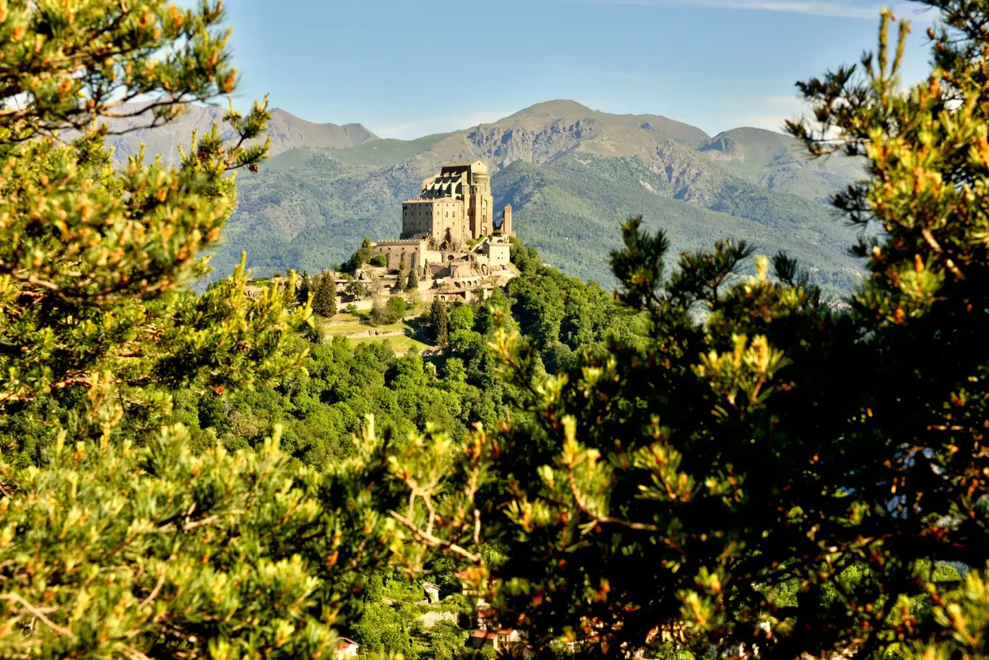 Picturesque landscape featuring the Sacra di San Michele surrounded by lush greenery in Piemonte, Italy.