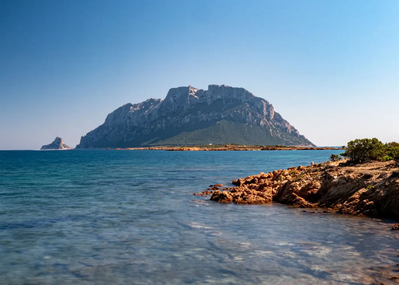Captivating summer view of Tavolara Island in Sardinia, featuring the rugged coastline and sparkling blue sea.