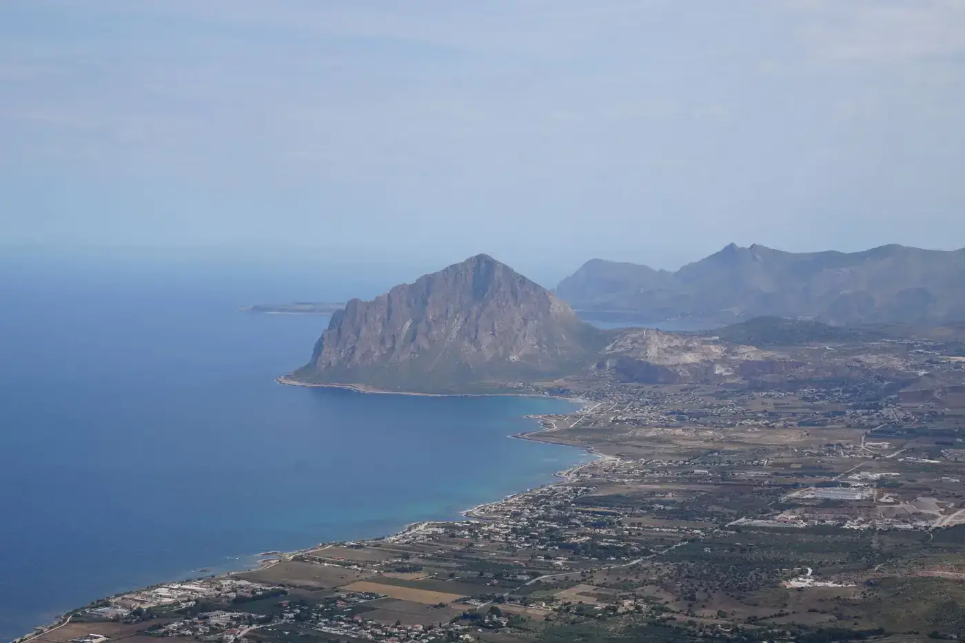 Stunning aerial view of the Sicilian coastline with a prominent mountain and clear Mediterranean sea.