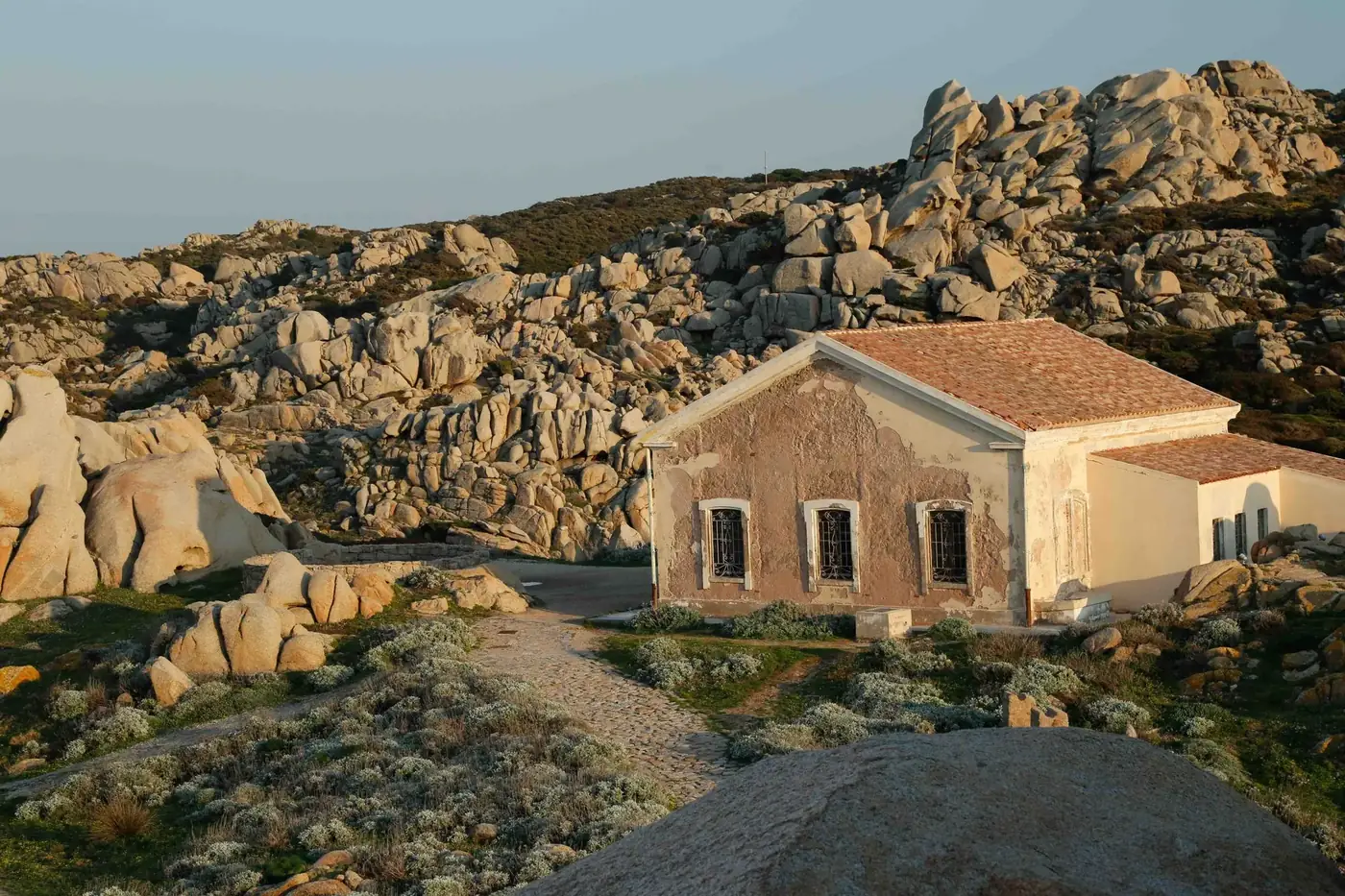 Old stone house surrounded by scenic rocky terrain, capturing a sense of tranquil isolation.