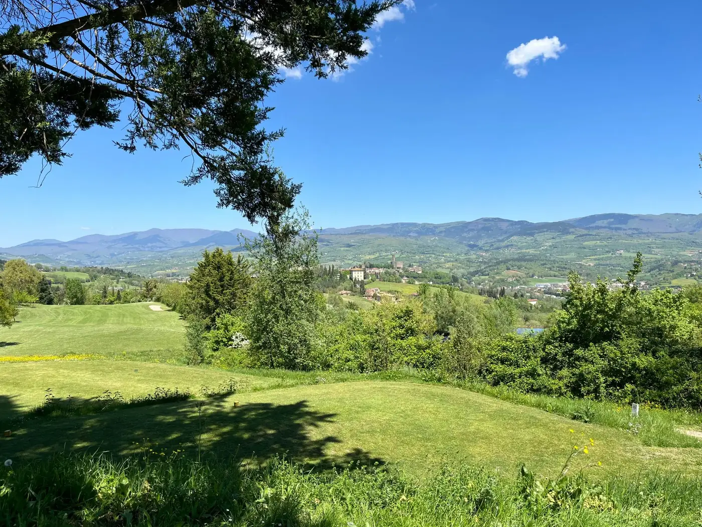 Beautiful landscape view of the green hills and countryside in Poppi, Tuscany, under a clear blue sky.