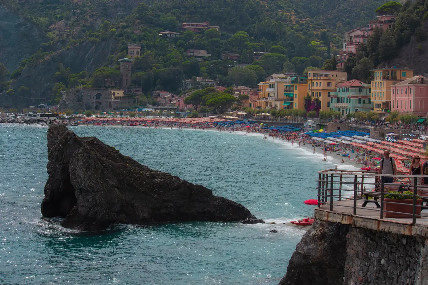 Colorful beach scene in Monterosso al Mare, Liguria, with cliff views and vibrant buildings.