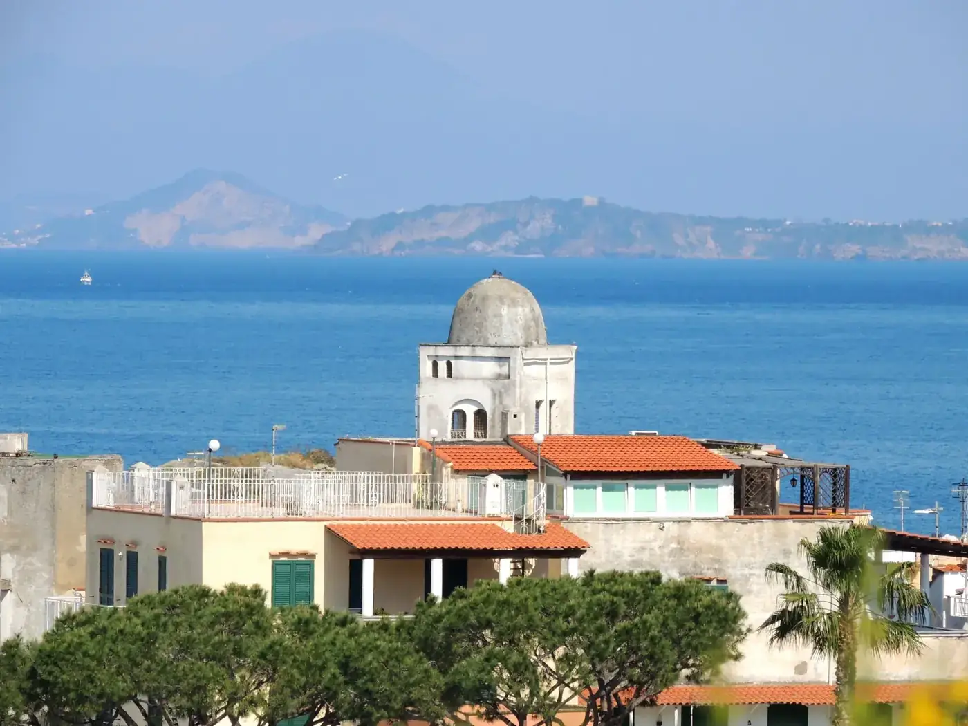 Charming coastal architecture with a serene view of Ischia Island's coastline and calm sea.