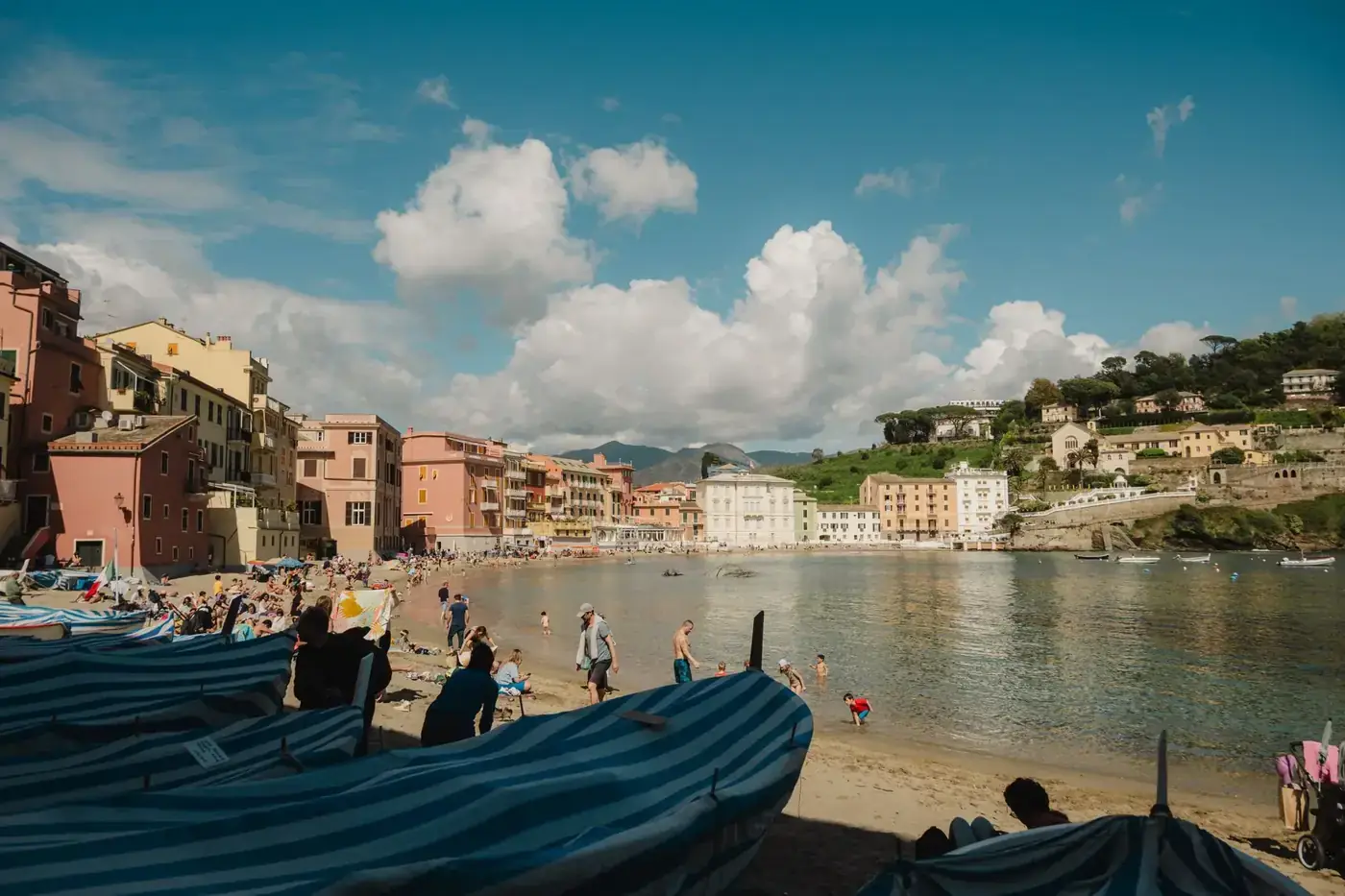 Sunny day at a lively Italian beach with colorful buildings and people enjoying the seaside.