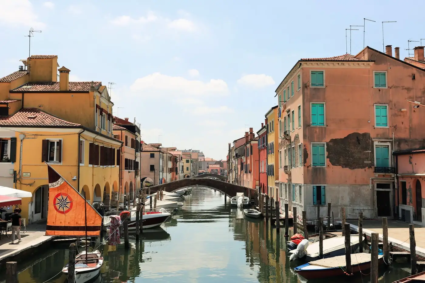 Picturesque canal scene in Chioggia with colorful buildings and boats under a sunny sky.