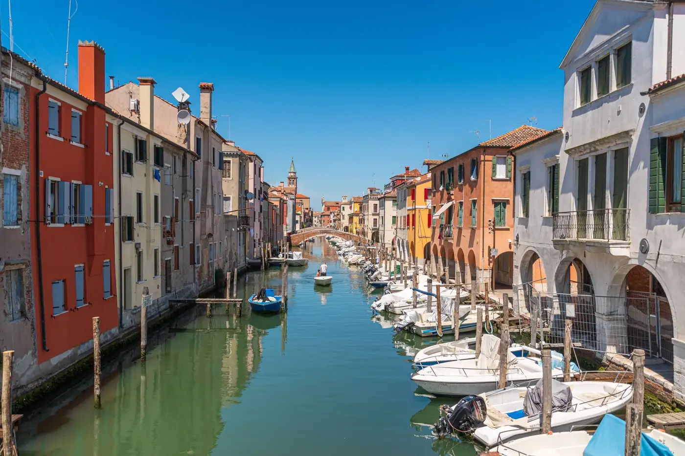 Colorful houses and boats line a picturesque canal in Chioggia, Italy.