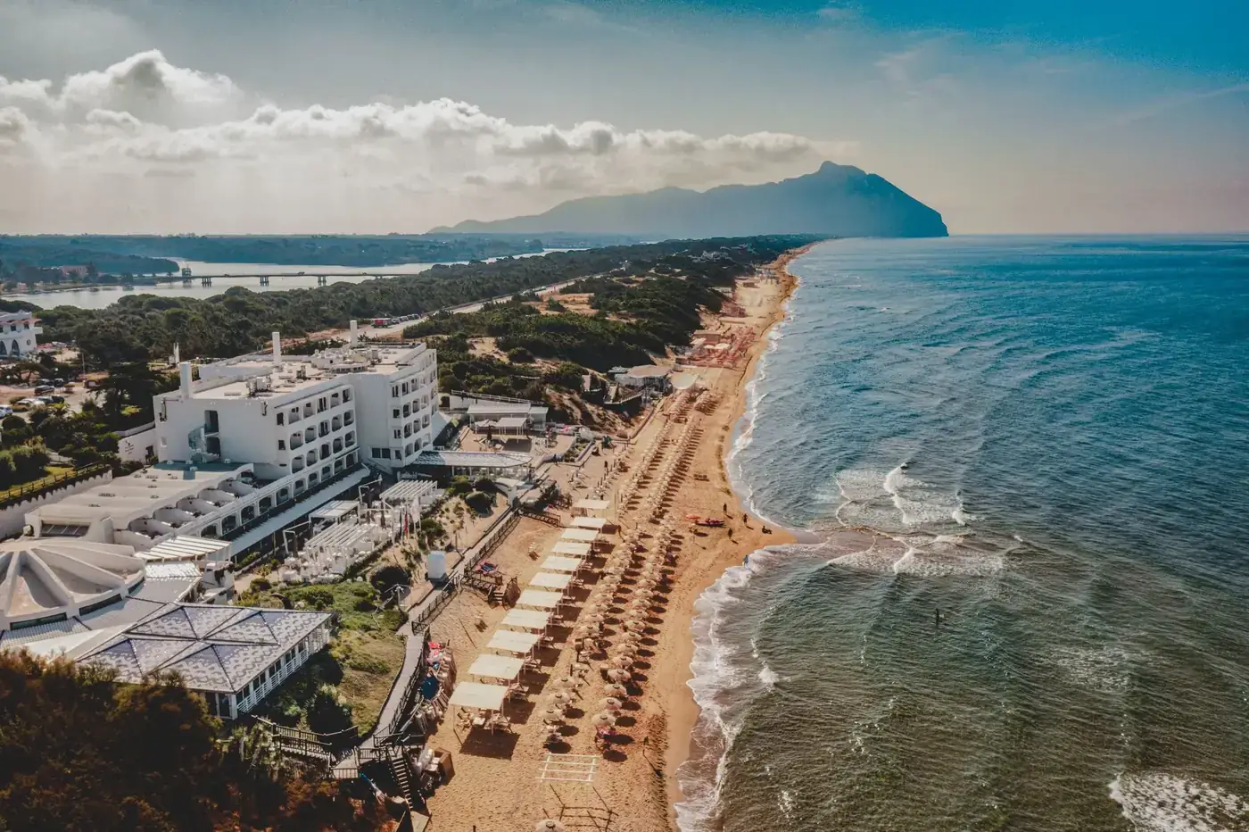 A picturesque aerial view of a beachfront in Lazio, Italy with clear waters and beach umbrellas.