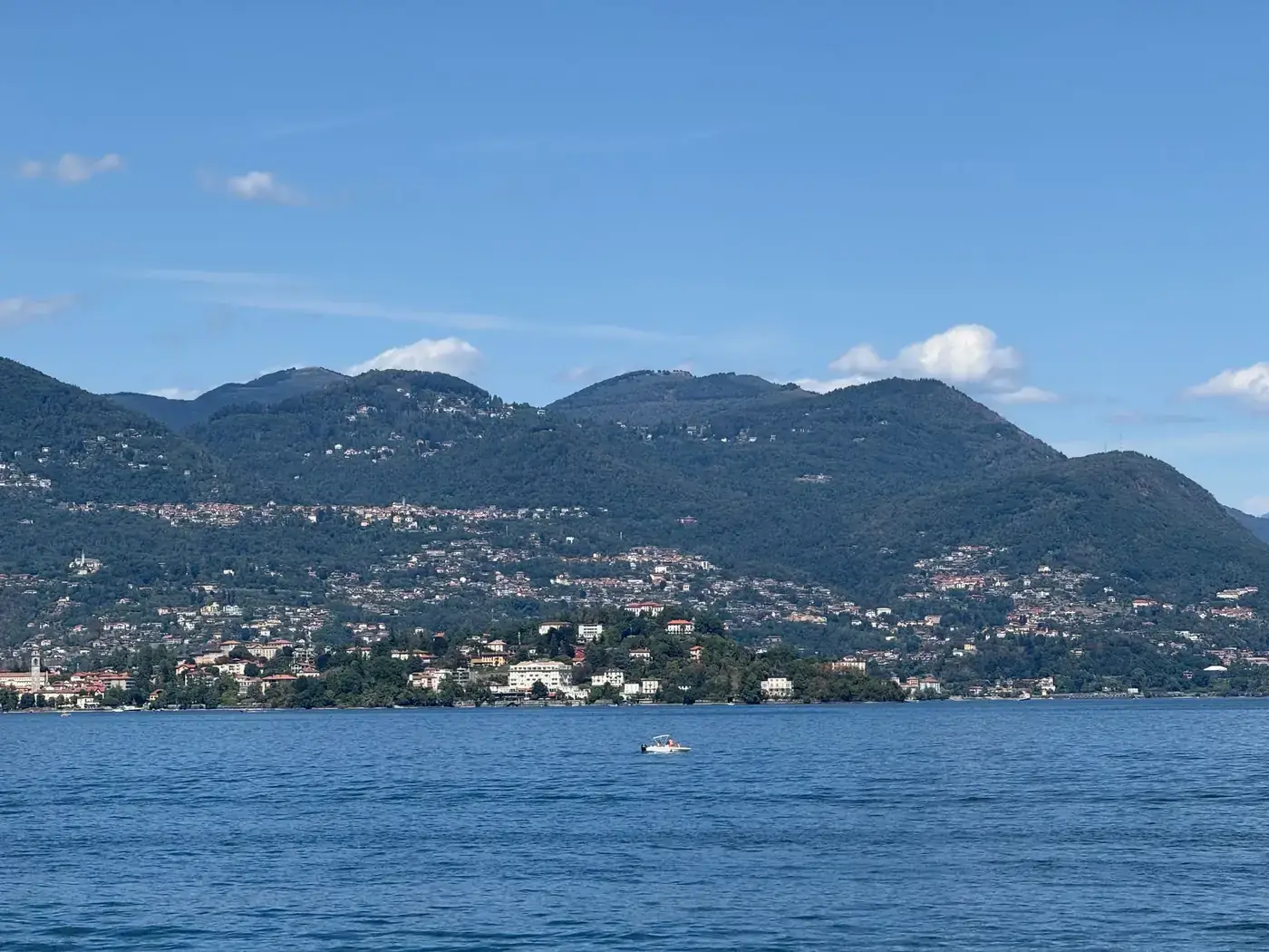Beautiful landscape of Lake Maggiore with lush mountain backdrop under clear blue skies.