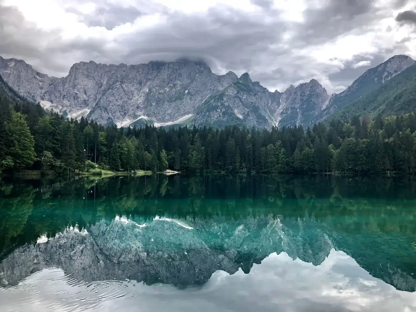 Breathtaking view of a tranquil mountain lake with clear reflections in Tarvisio, Italy.