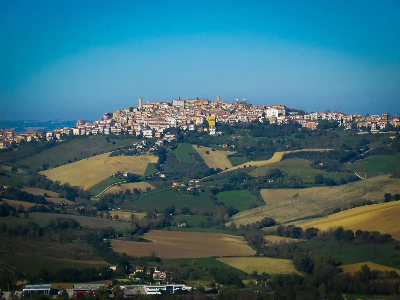 A picturesque hilltop town in Italy surrounded by lush green fields and vibrant landscapes.