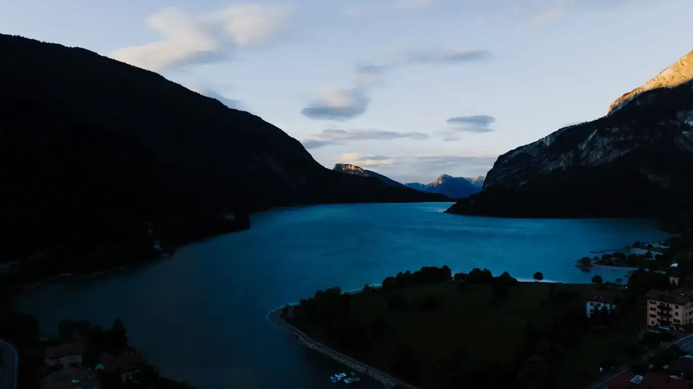 Peaceful Molveno Lake in the Italian Alps during twilight, surrounded by mountains.