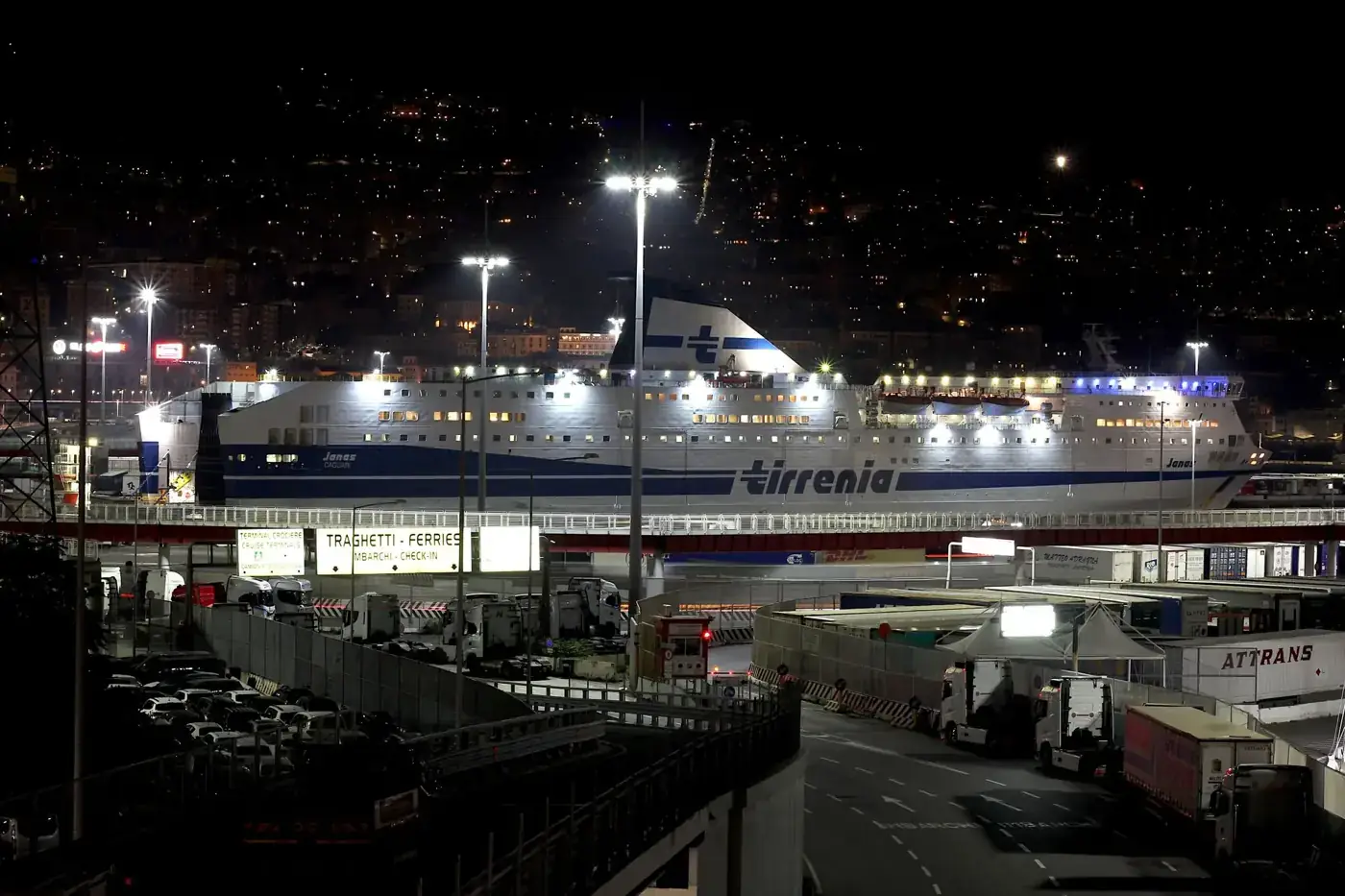 A brightly lit cruise ship moored at Genoa harbor under a starry night sky, showcasing urban maritime activity.