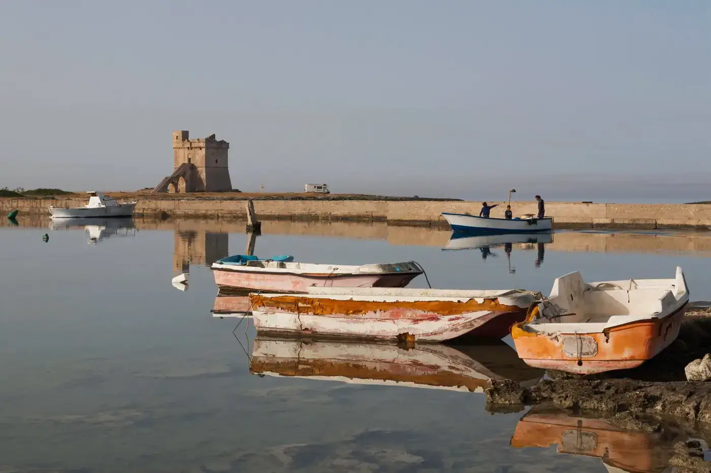 Weathered boats docked near Torre Chianca in Puglia, Italy, reflecting serene coastal beauty.