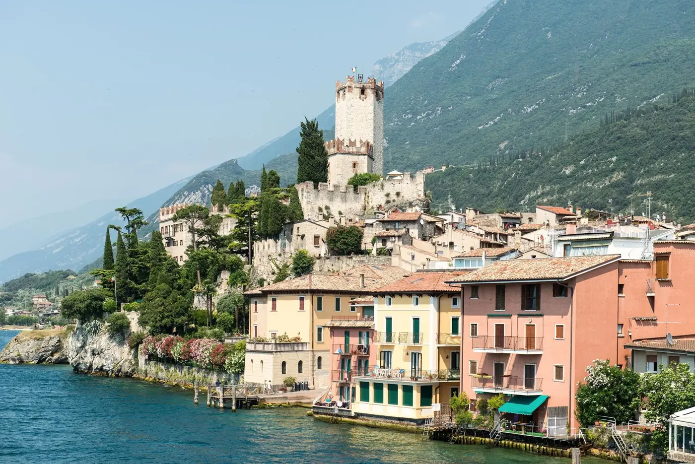 Picturesque town by Lake Garda with historic castle and colorful buildings in Italy.